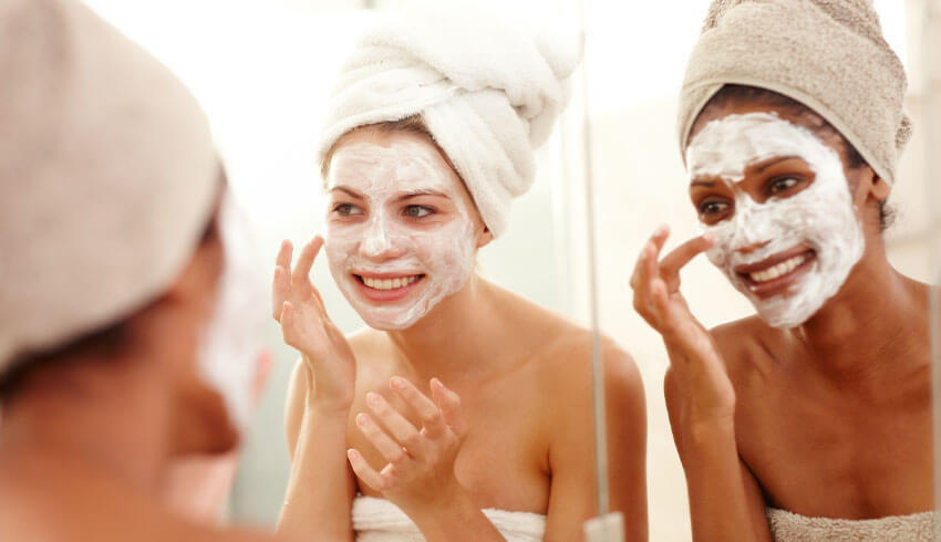 The reflection in a mirror of two women applying cosmetic face masks